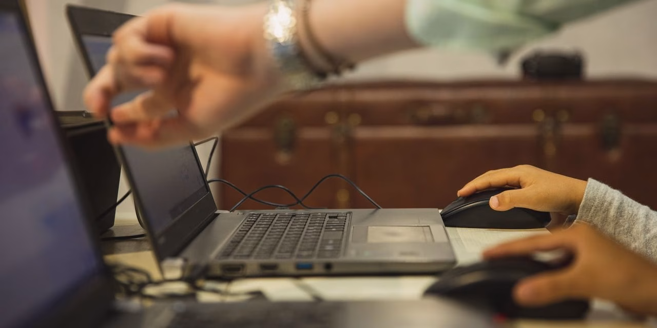 pexels-photo-5745520-5745520 Crop anonymous female teacher pointing at netbook screen near schoolchildren touching mouses at desk in classroom